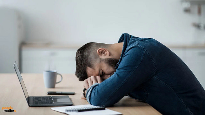 1731587001 A tired man in hid office bends down his head on the desk