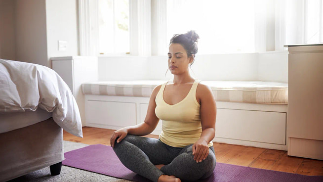 gettyimages-954596030 A woman doing yoga at home