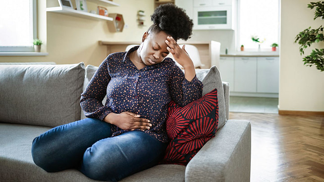 A woman in distress sitting on a sofa with hand on the head