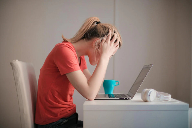 pexels-photo-3755761 A frustrated woman sitting before a laptop with hands over her head