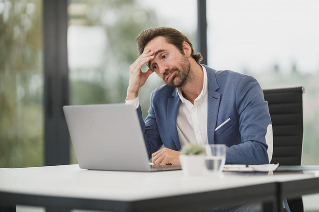 stressed-businessman-at-desk-with-laptop stressed businessman at desk with laptop