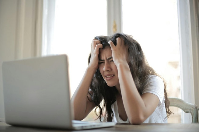 1716322661542 A depressed woman sitting with a laptop with her hands over the head