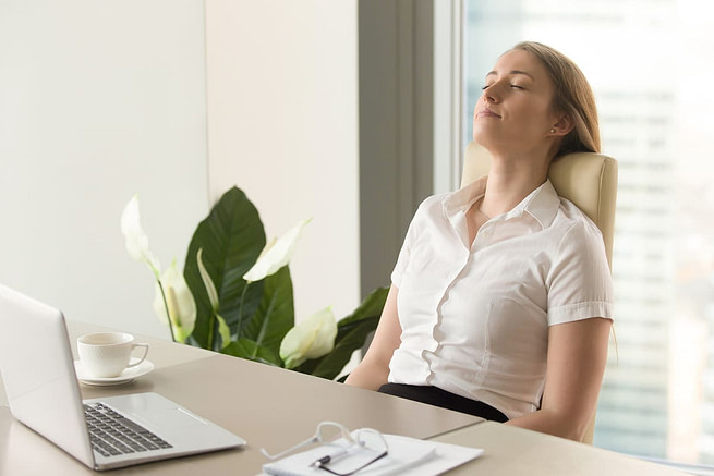 Breathing-Tips-to-Help-Control-Your-Anger A woman in office taking deep breath leaning on a chair