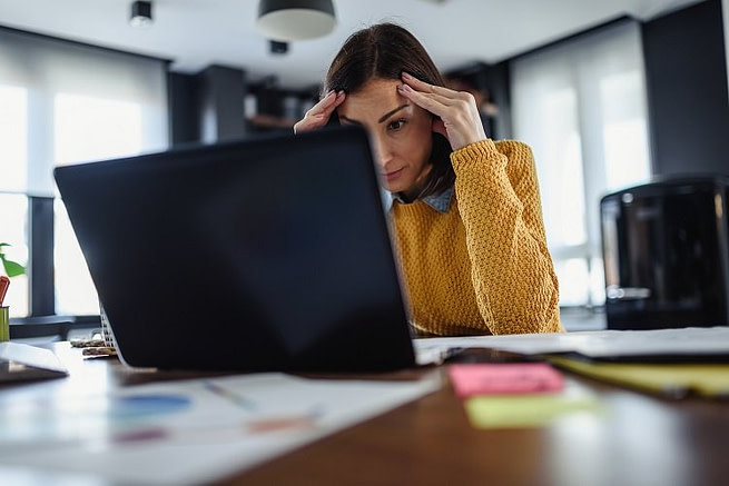 HDMindselectionstresscrop A woman tensed and keeping her hands on her head sitting in front of a laptop